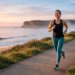 lt="A healthy, active woman jogging on a coastal path at sunrise, smiling and full of vitality. In the background, a modern medical infographic sign reads: 'Heart Prevention Is Better Than Cure: Tracking Your Numbers [AHA/ESC Data]'. The scene is authoritative and inspirational."